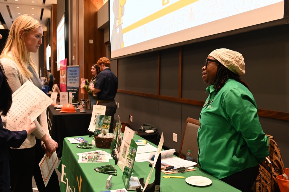 A recruiter speaks with a student at a career fair booth