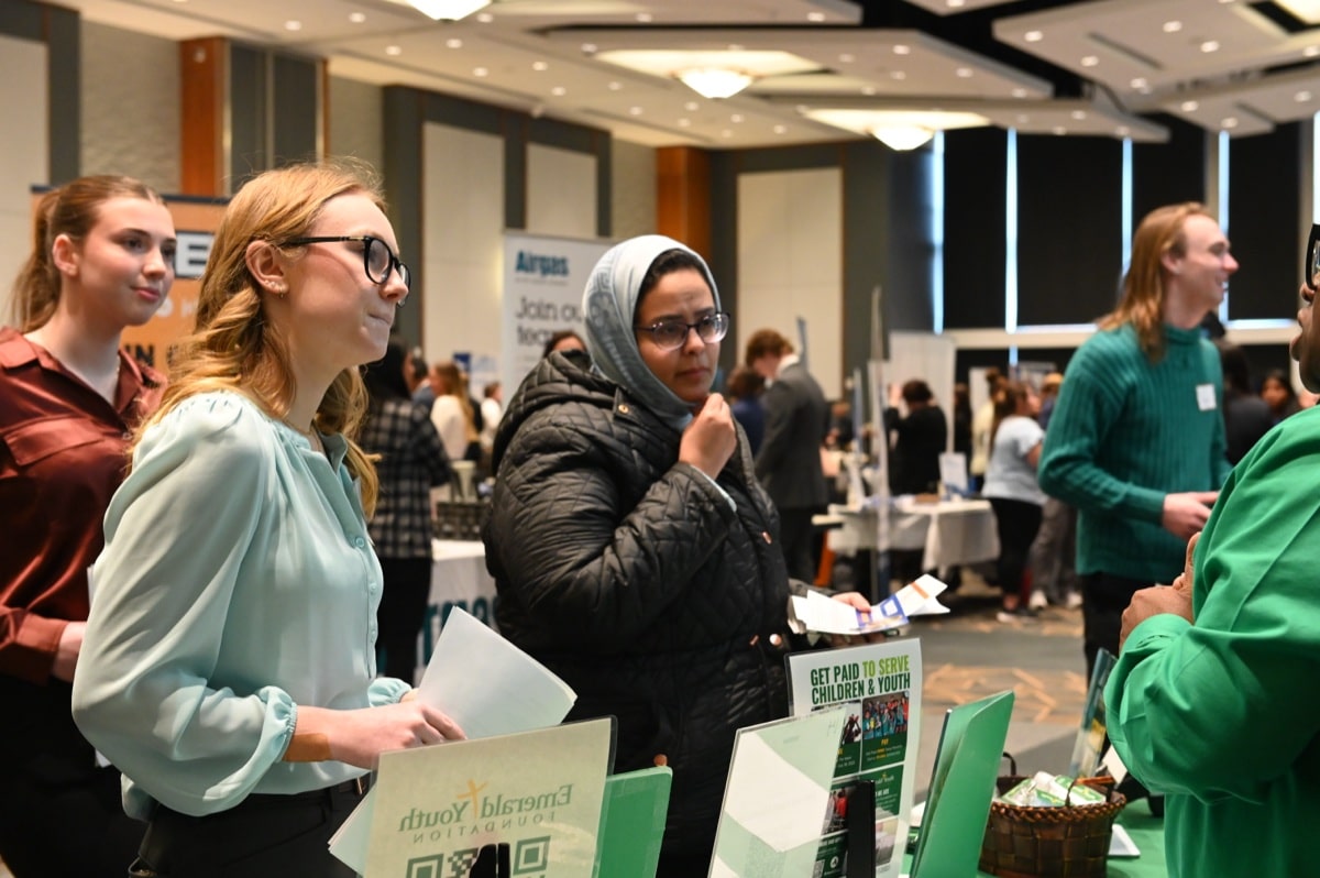 A recruiter speaks with a student at a career fair booth