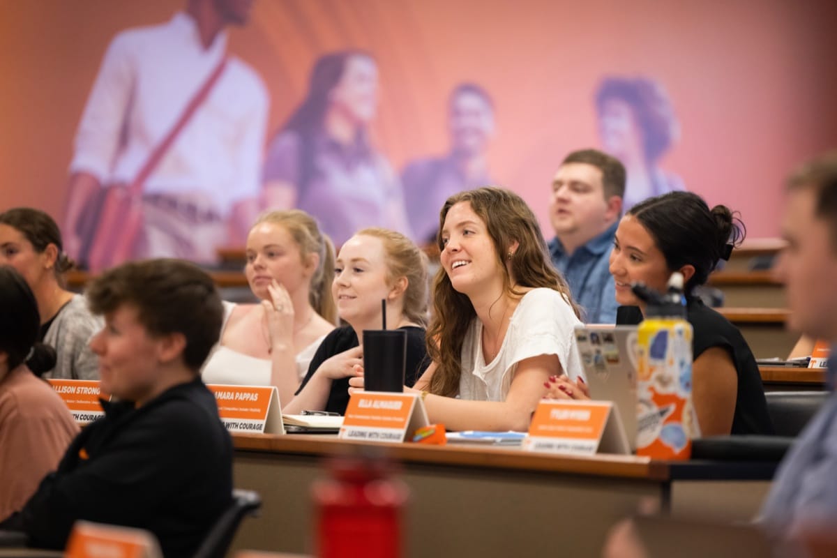 Students smile and listen to a speaker during a class in a UT lecture hall