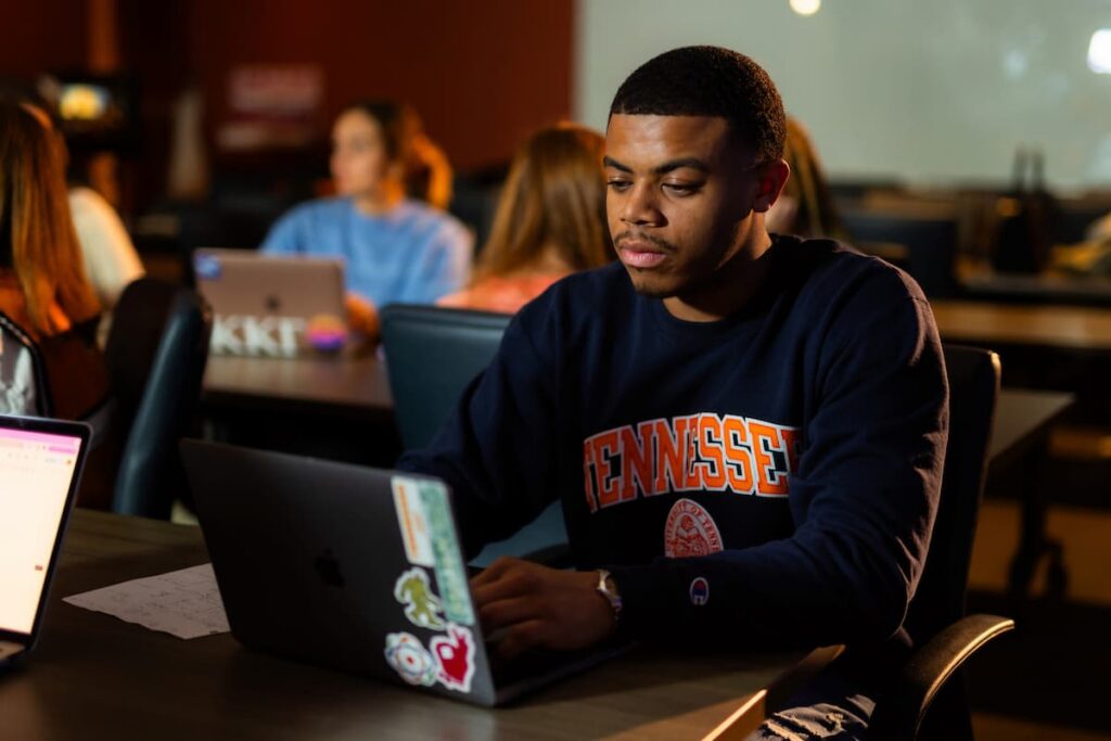 Student in a Tennessee sweatshirt working on a laptop in a campus study space