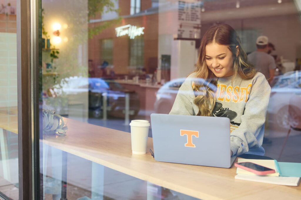 student sitting with a laptop in a coffee shop